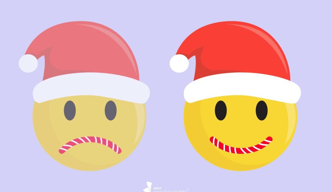 Cartoon shows two emojis. The one on the left is wearing a Santa hat and has a candy-cane mouth shaped into a frown, but the image is faded. the one on the right is bright, wearing a Santa hat and its candy-cane mouth is smiling