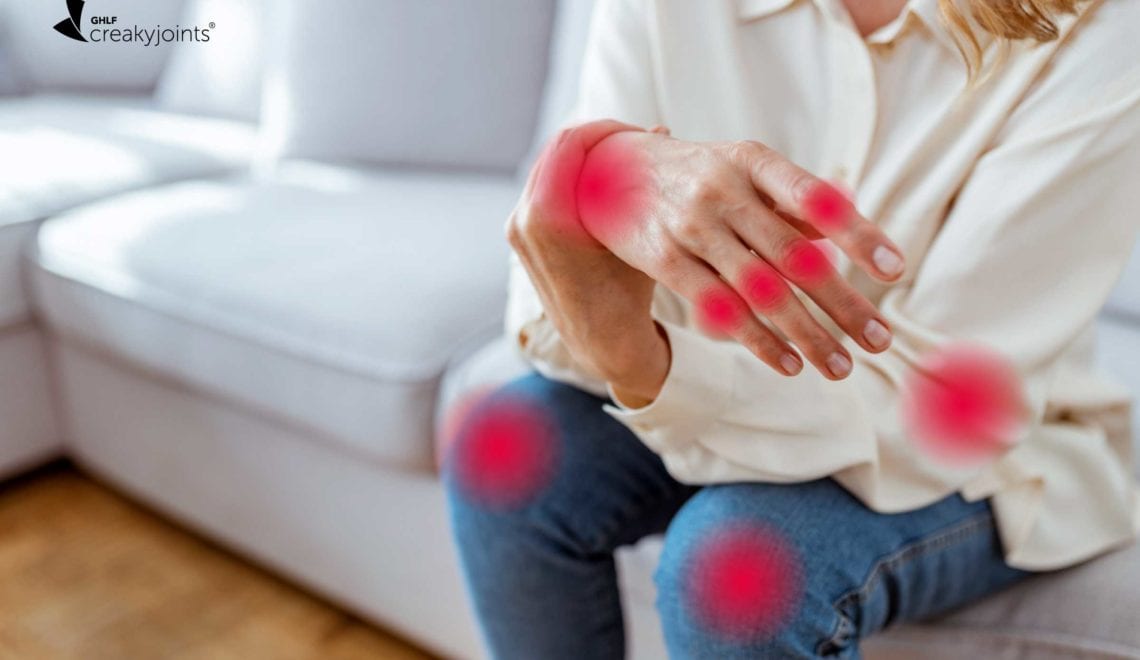 Photograph shows a woman sitting on a couch. She has red spots indicating joint pain