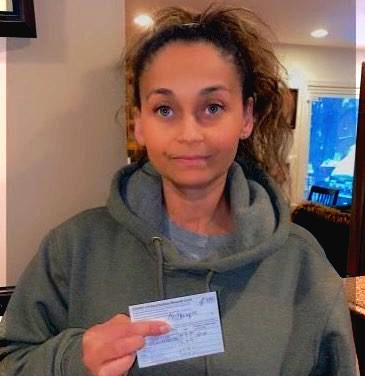 Photo of a healthcare worker holding her vaccine card