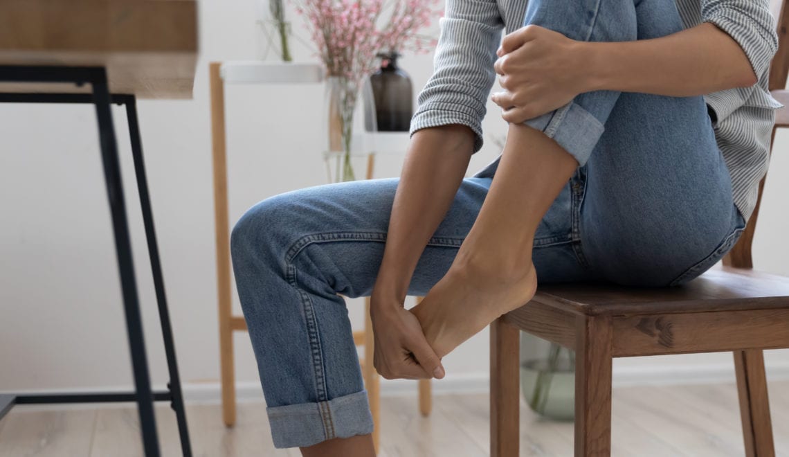 A close up of a woman massaging her foot to help relieve pain.