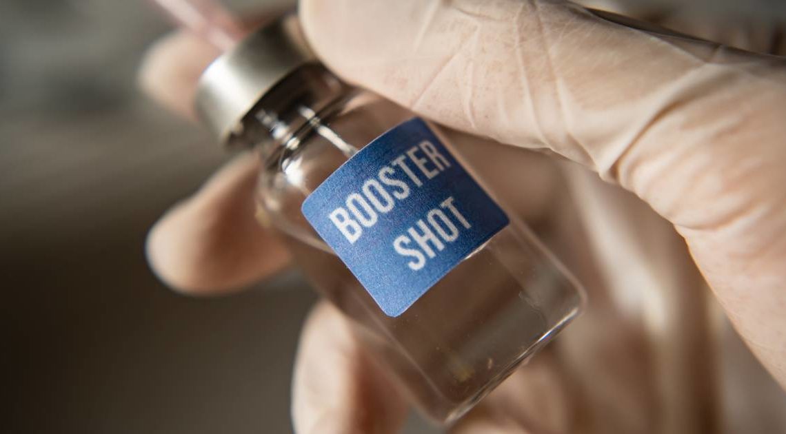 A medical professional holding a vial that reads "Booster Shot" on it.