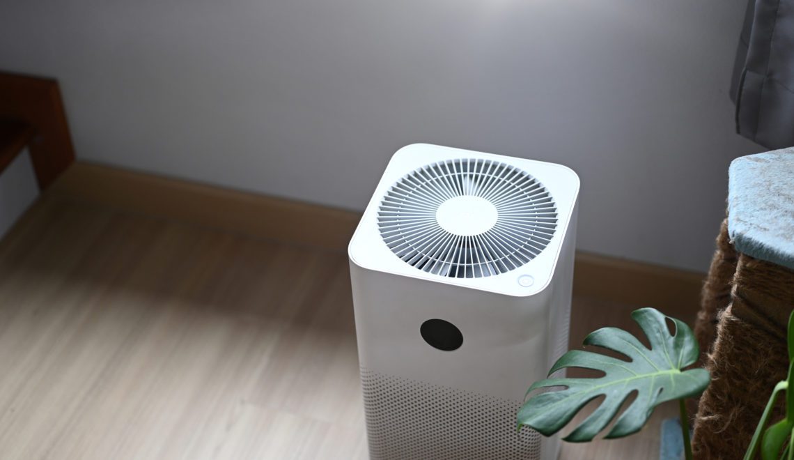 Air purifier in comfortable living room with house plant on the wooden floor.