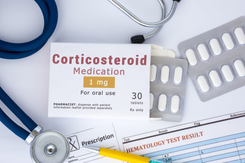 A corticosteroid medication or drug concept photo. On doctor table lies open packaging labeled "Corticosteroid medication" and fell out of blisters with pills treatment