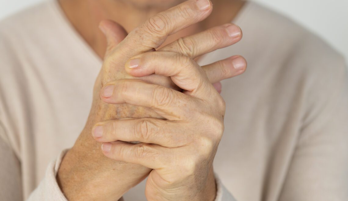 Older woman grasping hands with arthritis