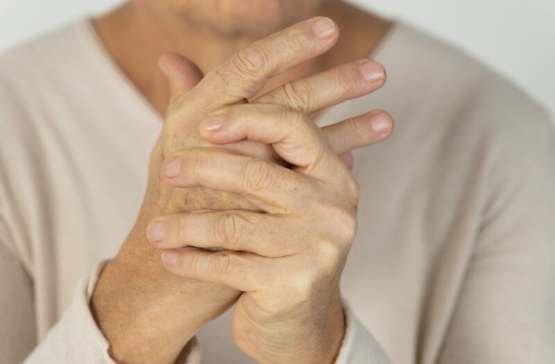 Older woman grasping hands with arthritis