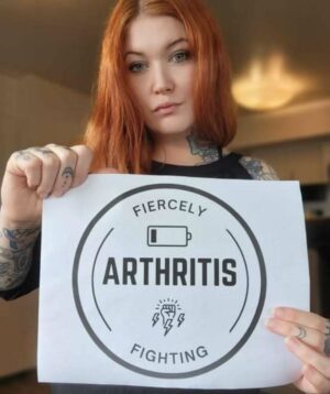 Image of woman holding a printed out sign that says 'fiercely fighting arthritis'