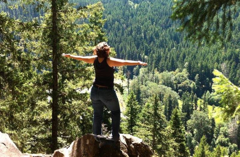 A photo of Angie Ebba, a woman with ankylosing spondylitis, standing on top of a mountain after a hike.