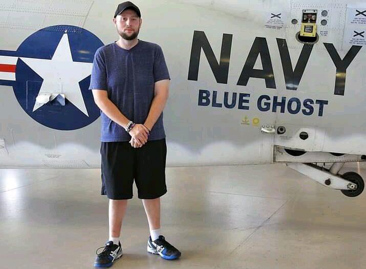 Photo of Russ Miller, a man who lives with rheumatoid arthritis. He is standing in front of a plane that says Navy Blue Ghost.