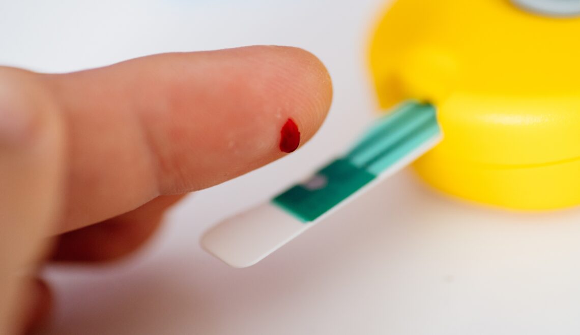 Photo of a person using a glucose meter to prick their finger and test blood sugar with type 2 diabetes