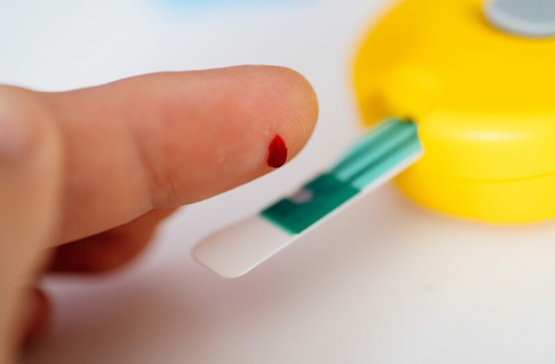 Photo of a person using a glucose meter to prick their finger and test blood sugar with type 2 diabetes